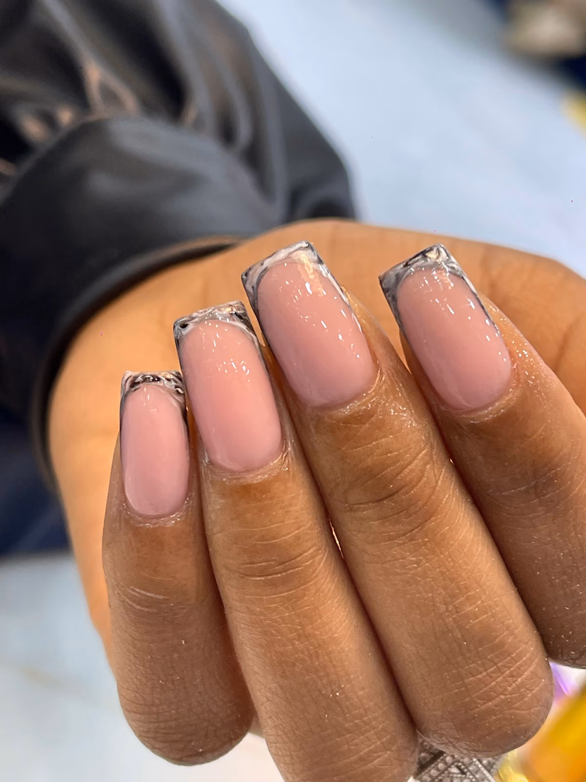Short square nails with clear tips and a silver glitter French outline